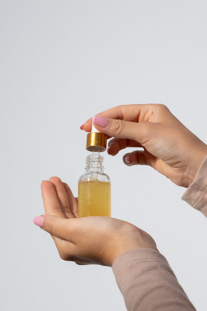 Person's Hands Holding a Bottle of Serum